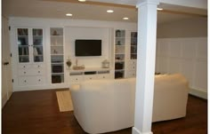 a living room with white furniture and built in bookshelves on the side wall