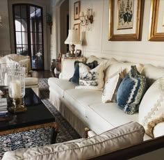 a living room filled with white couches and lots of pillows on top of them