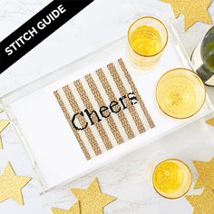 two glasses and one bottle on a tray with some gold stars around it that says cheers