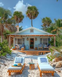 two chaise lounges on the beach in front of a house with palm trees