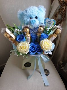 a blue teddy bear sitting on top of a chair next to a bouquet of flowers