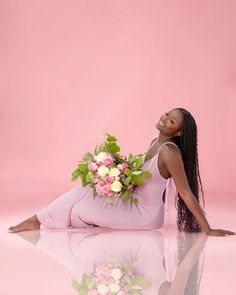 a woman sitting on the ground with flowers in her lap