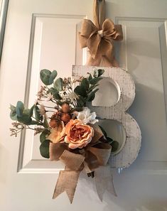 a wooden letter decorated with flowers and greenery hangs on the front door's wall