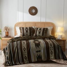 a bed with a brown and white blanket on top of it next to a night stand