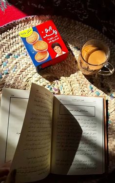 an open book sitting on top of a table next to a cup of tea and coffee