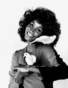 a black and white photo of a woman holding a bird