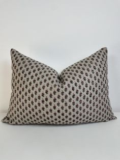 a black and white pillow sitting on top of a white table next to a wall