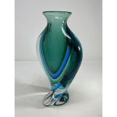 a green and blue vase sitting on top of a white table