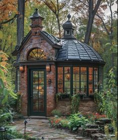 a small brick building in the middle of a garden with lots of plants and flowers