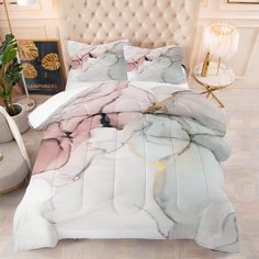 a bed with a white and pink comforter on top of it next to a chair