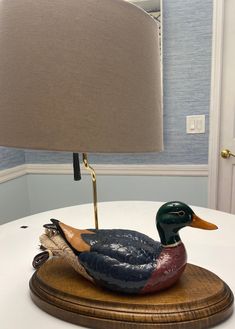 a wooden duck lamp sitting on top of a table next to a light fixture with a beige shade