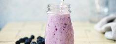 a blueberry smoothie in a mason jar with a straw sticking out of it