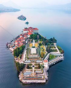 an island in the middle of water with buildings on it and lots of greenery