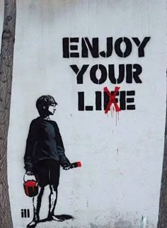 a painting on the side of a building that says enjoy your life with a boy holding a bucket