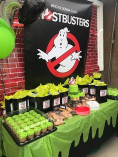 a table with green cupcakes and other desserts on it in front of a ghost sign