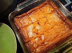 a square cake sitting on top of a pan next to a green plate and bowl