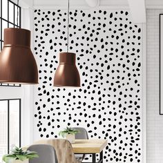 a dining room with black and white polka dots on the wall, two pendant lights hanging from the ceiling