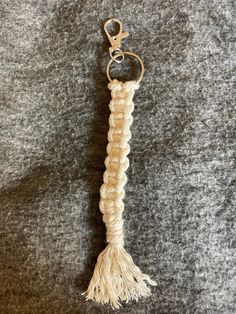 a rope keychain with a tassel hanging from it's end on a gray surface