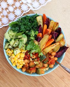 a blue bowl filled with vegetables on top of a wooden table