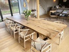 a large wooden table sitting in the middle of a living room next to a stair case