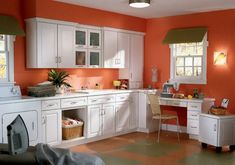 a kitchen with orange walls and white cabinets