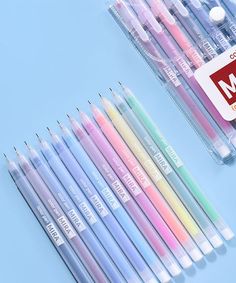 many different colored pens are lined up on a blue surface with a red and white sign in the middle