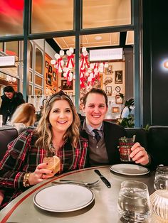 two people sitting at a table with plates and drinks