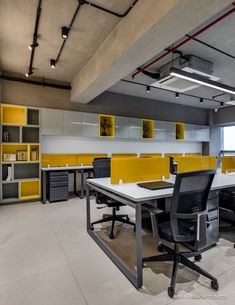 an office with yellow and gray cabinets, black chairs, and white table in the middle