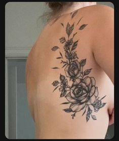 a woman's back with flowers and leaves tattooed on her left side ribcage