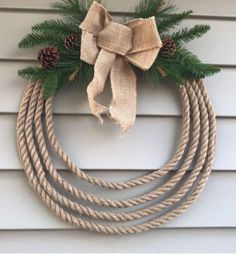 a christmas wreath with pine cones and burlocks hanging on the side of a house