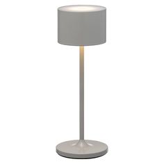 a lamp that is on top of a white table cloth and has a light in the middle