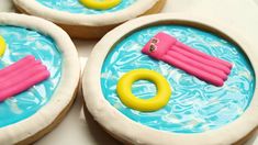 three decorated cookies in the shape of boats and life rings on top of blue water