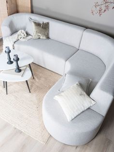 a white couch sitting on top of a wooden floor next to a table with two candles