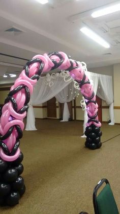 some black and pink balloons are in the middle of a room