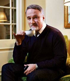 a man sitting in a chair drinking from a cup