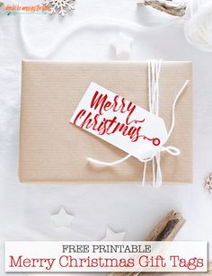 a christmas gift tag on top of a brown box with white string and red lettering