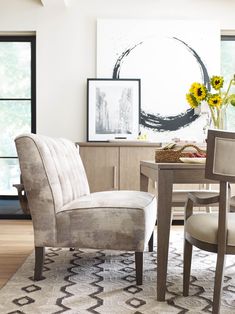 a dining room table and chairs with sunflowers in the vase next to them