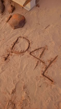 the word love is written in the sand next to some rocks and a wooden bench