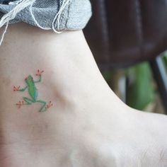 a small green frog tattoo on the ankle