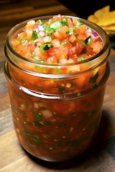 a jar filled with salsa sitting on top of a wooden table