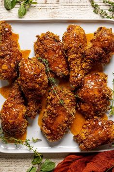 chicken wings covered in sauce and herbs on a white plate