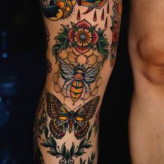 a woman's leg with tattoos on it and a bee in the center, surrounded by flowers