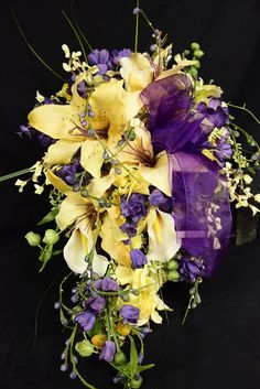 a bouquet of yellow and purple flowers on a black background with greenery around it