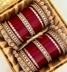 three rows of red bangles in a box with gold trimmings on them