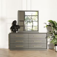 a large mirror sitting on top of a dresser next to a potted plant