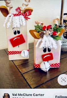 two paper bags decorated like reindeers on top of a wooden table next to each other