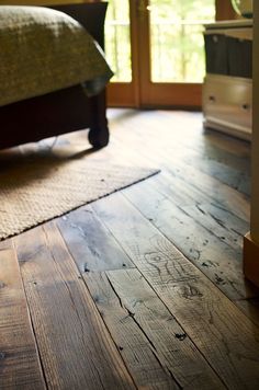 a bed room with a neatly made bed and wooden floors