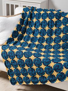 a crocheted blue and yellow blanket with gold stars on it sitting on a bed