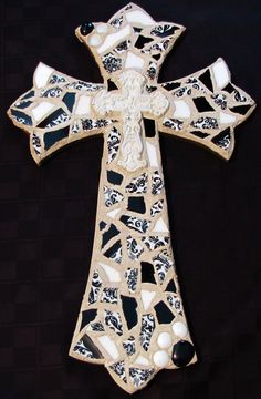 a decorative cross made out of glass and marbles on a black background with white accents