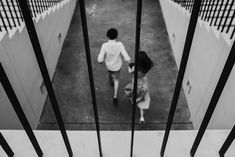 black and white photograph of two people walking down the stairs in an jail cell area